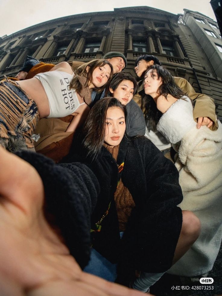 a group of young women taking a selfie in front of a tall building on a sunny day