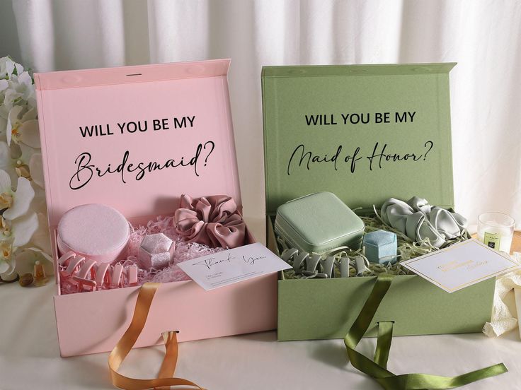 two bridesmaid gift boxes are sitting on a table next to ribbons and flowers