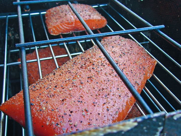 two raw salmons cooking on the grill