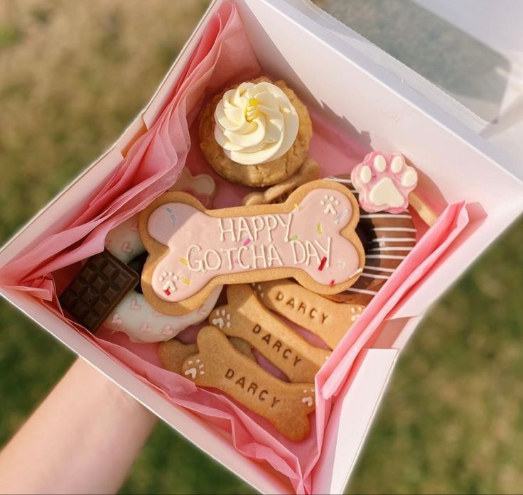 a person is holding a box full of cookies and pastries that say happy coichday