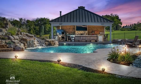 an outdoor pool surrounded by landscaping and lighting