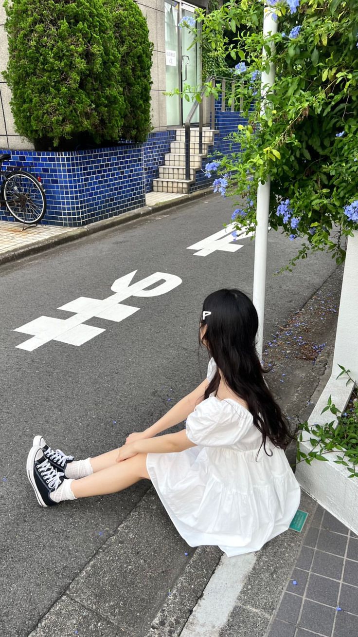 a woman sitting on the side of a road