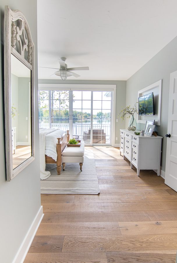 a living room filled with furniture and a large mirror on top of a wooden floor