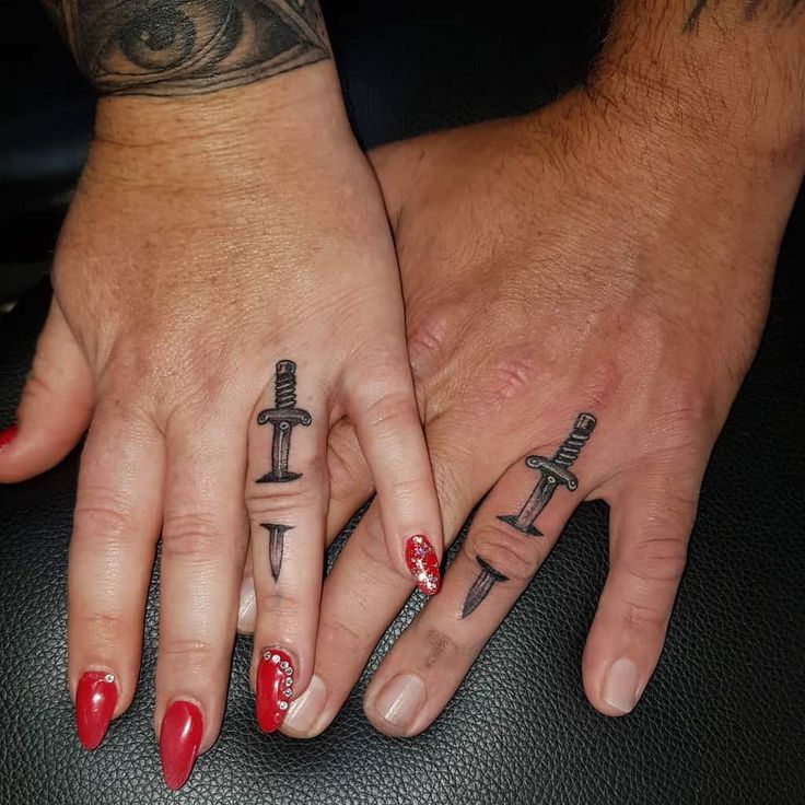 two people with matching tattoos on their hands holding each other's fingers and one has a cross tattoo on it