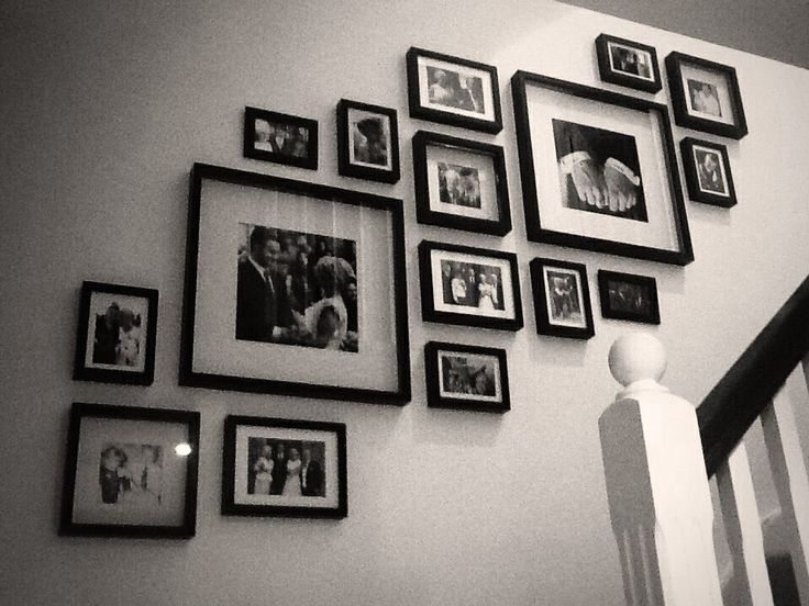 black and white photo hanging on the wall next to stair railing with many frames around it