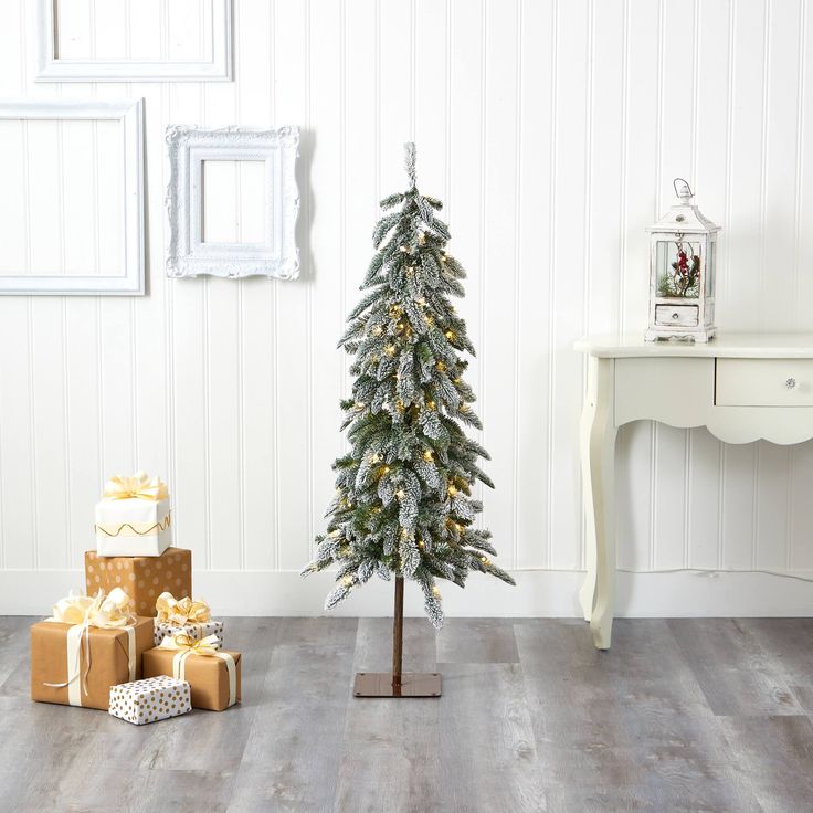 a small christmas tree in a room with presents on the floor and wall behind it