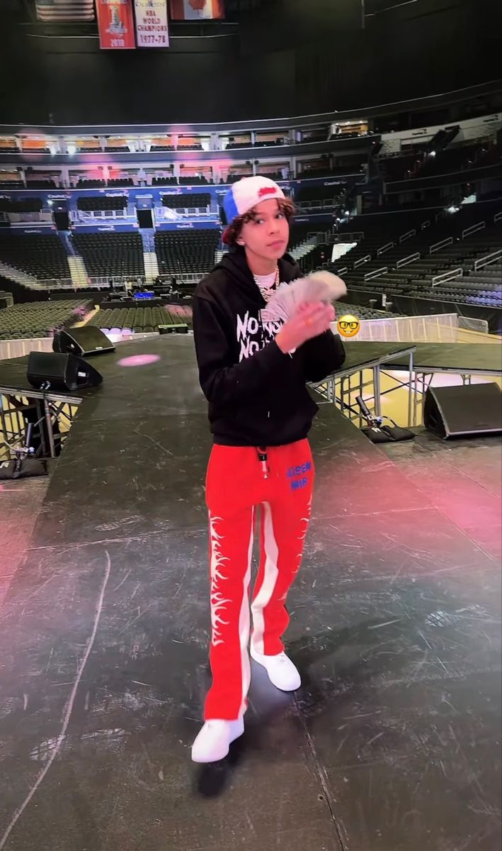 a young man standing in front of an empty arena with his hands out to catch a frisbee