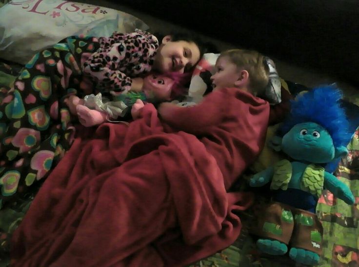 two small children sleeping next to each other on a bed with stuffed animals and blankets