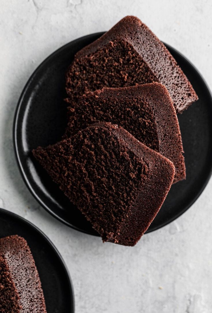 three slices of chocolate cake on black plates