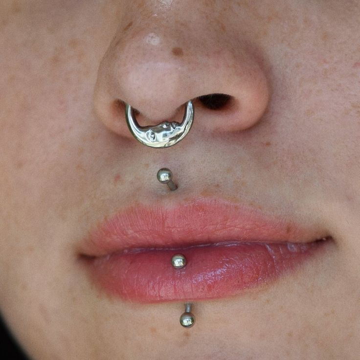 a woman's nose with piercings on top of her nose and the bottom part of her nose