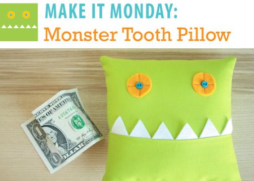 a green monster pillow sitting on top of a wooden table next to a dollar bill