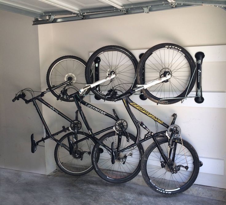 three bikes are mounted to the wall in a bike storage area with two bicycles hanging from it's hooks