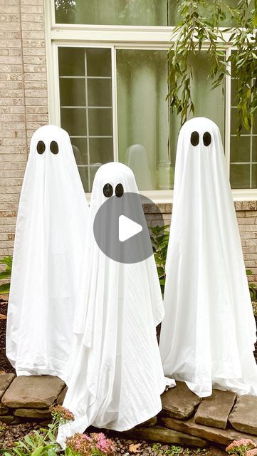 two white ghost statues in front of a house