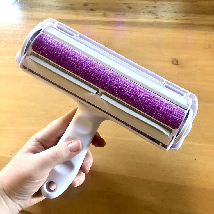 a hand holding a hair dryer on top of a wooden table next to a wood floor