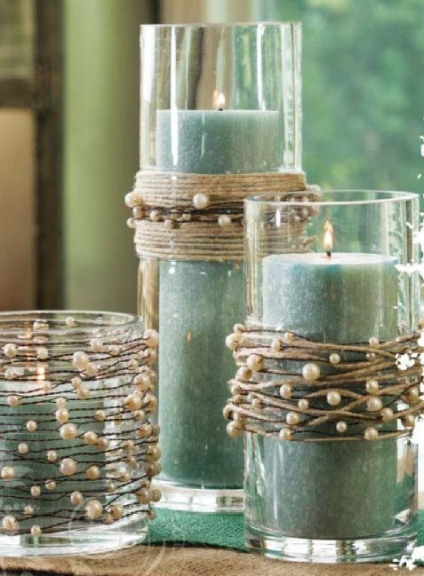 three candles are sitting on a table with beads and twine wrapped around the candle holders