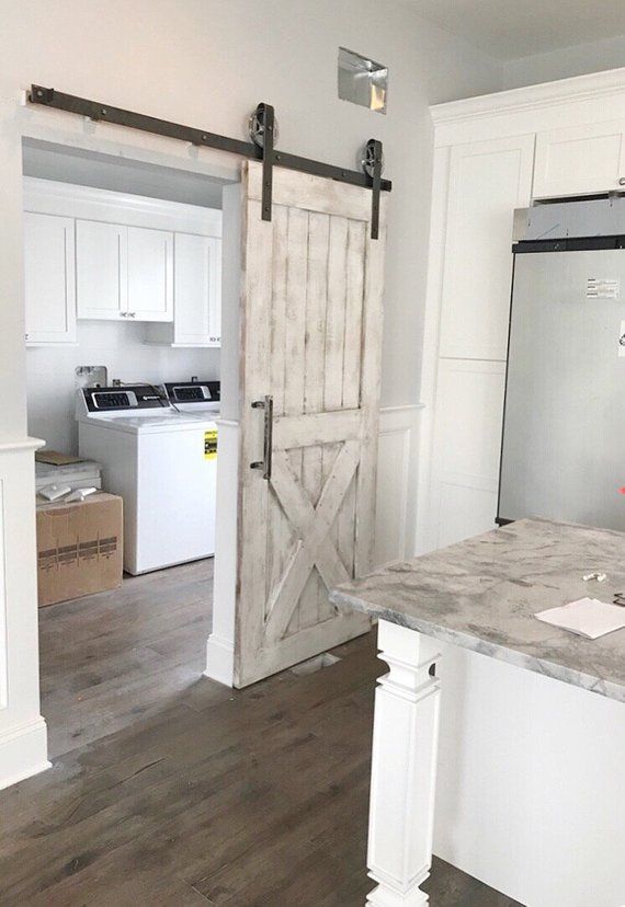 a kitchen with an open barn door and white cabinets