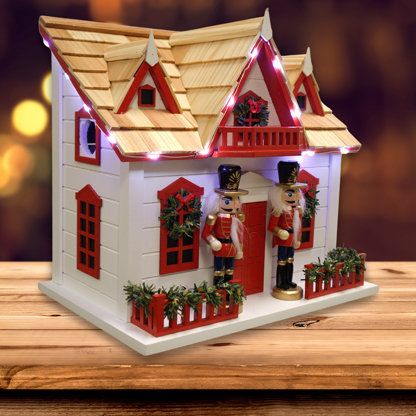 a toy house with lights and decorations on the roof is sitting on a wooden table