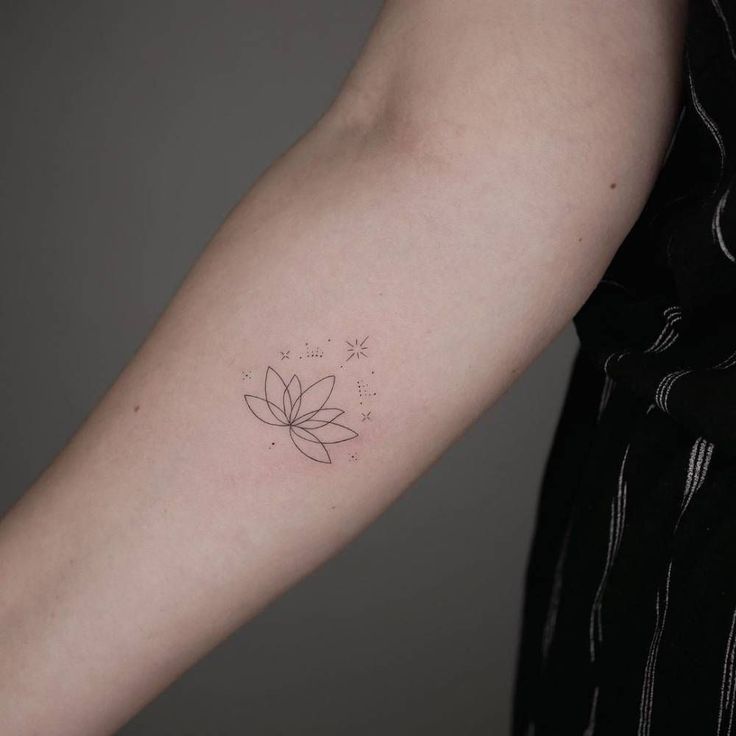 a woman's arm with a small flower tattoo on the left side of her arm