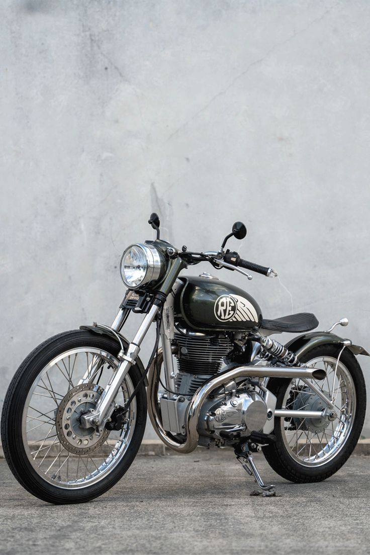 a black motorcycle parked in front of a cement wall