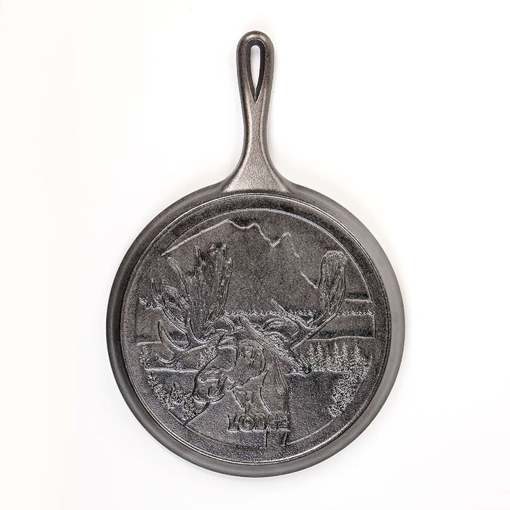 an old cast iron frying pan with animals on it's front and sides