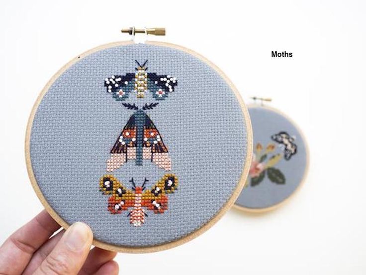 two cross stitch hoops with designs on them, one is blue and the other is orange