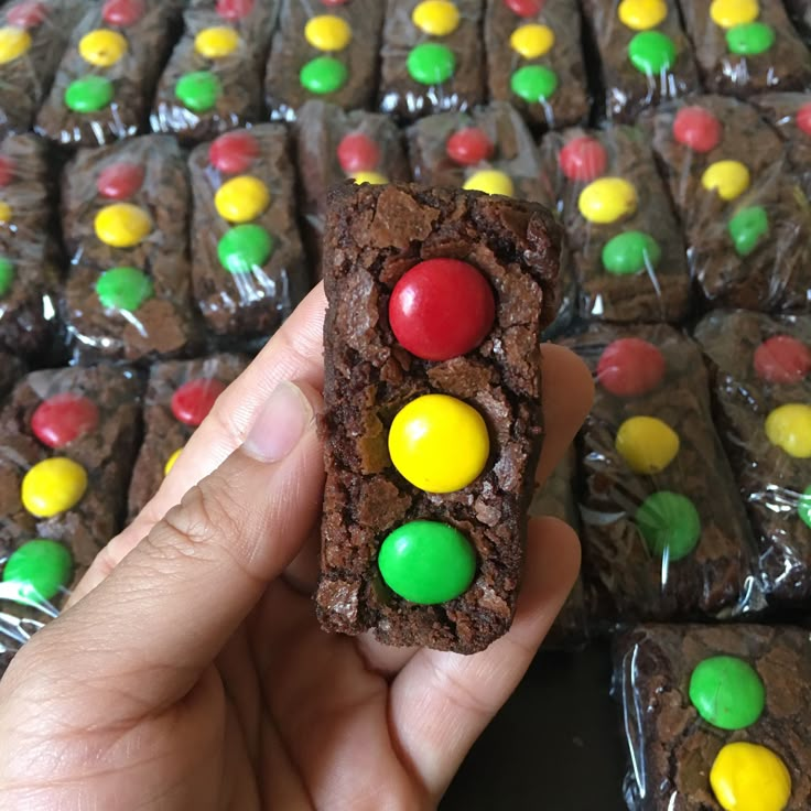 a hand holding up a chocolate cookie with m & m candies on it