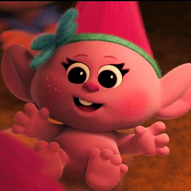 a pink troll with a green headband and big eyes is standing in the middle of a room