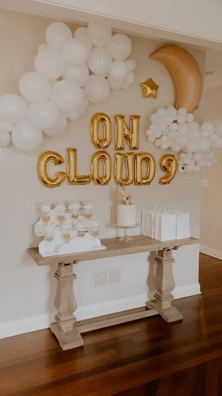 a table topped with balloons and cake next to a sign that says on clouds above it