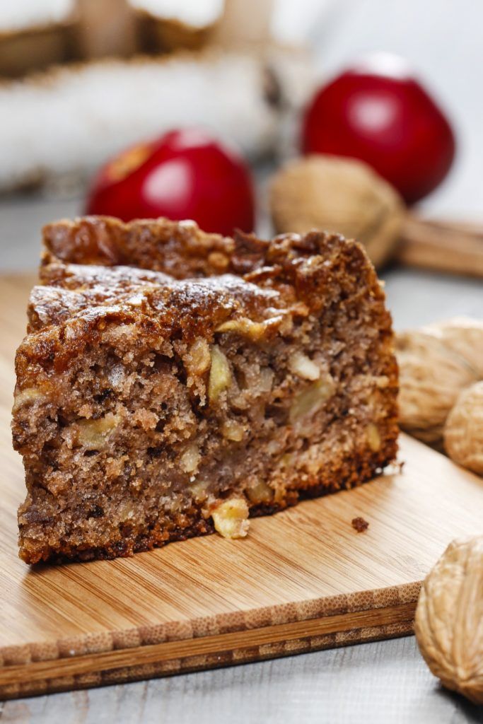 a piece of cake sitting on top of a wooden cutting board next to some nuts