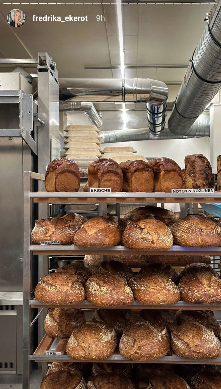 breads and rolls are stacked on shelves in a bakery