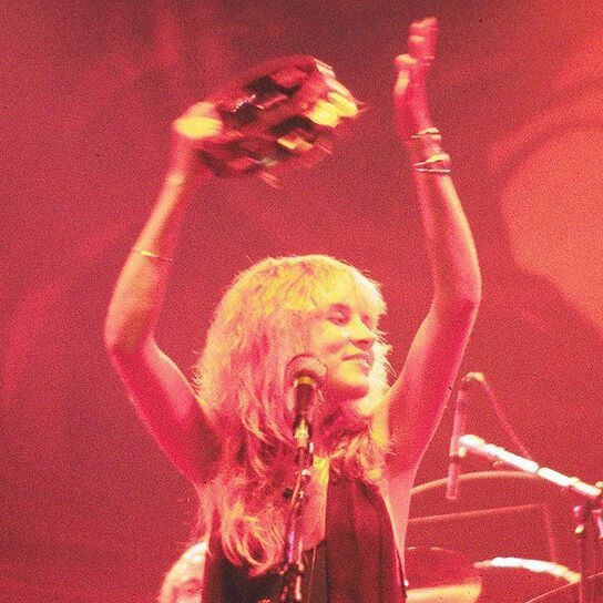 a woman with her arms up in the air while holding a glove above her head