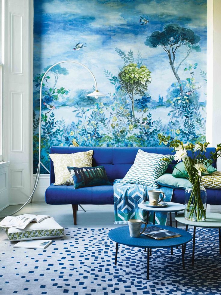 a living room with blue couches and wallpaper on the walls in front of it