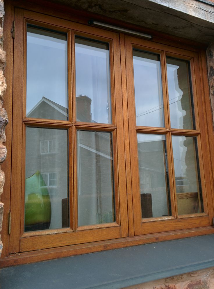 a green vase sitting on the window sill in front of a stone building with windows