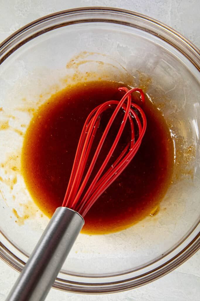 a whisk in a glass bowl filled with brown liquid