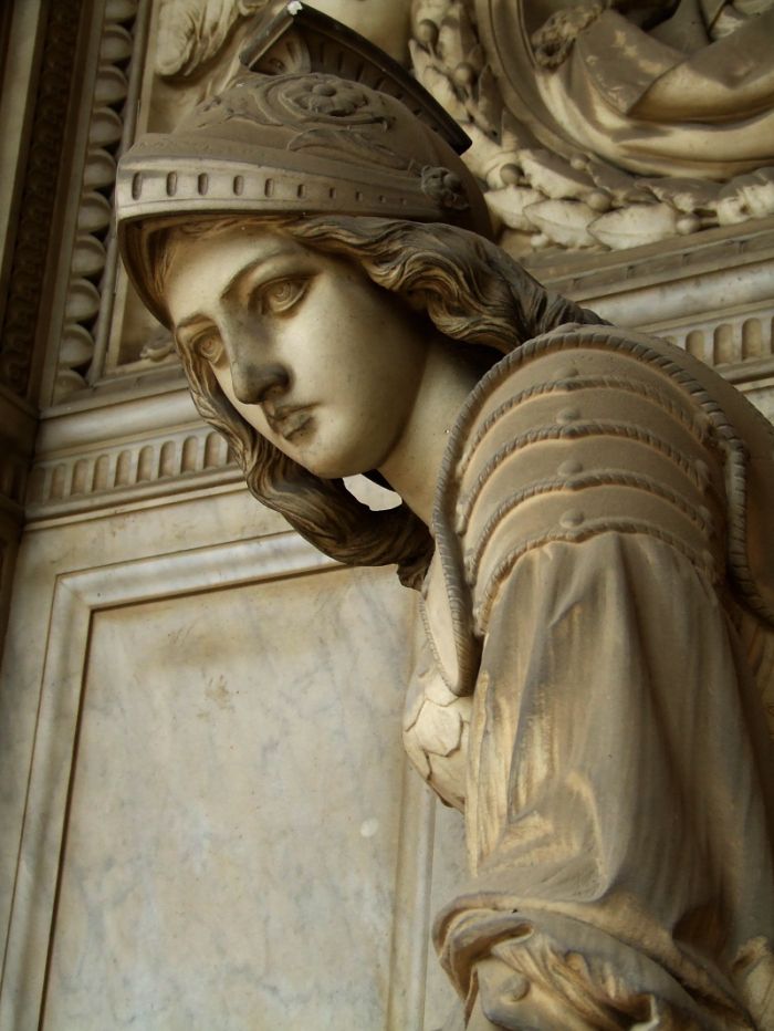 a statue of a woman with a crown on her head is in front of a wall