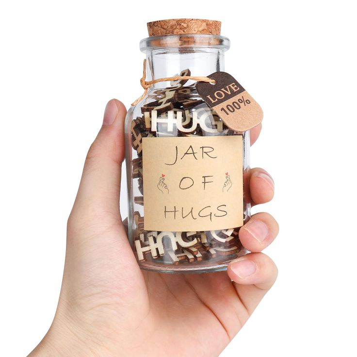 a person holding up a jar filled with lots of coins that say hug, jar of hugs