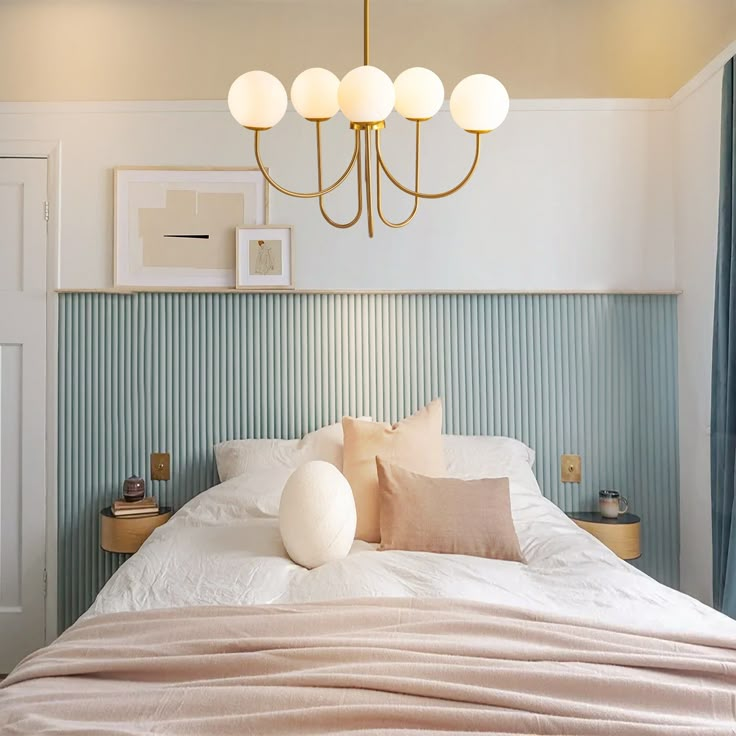 a bedroom with a bed, chandelier and pictures on the wall above it