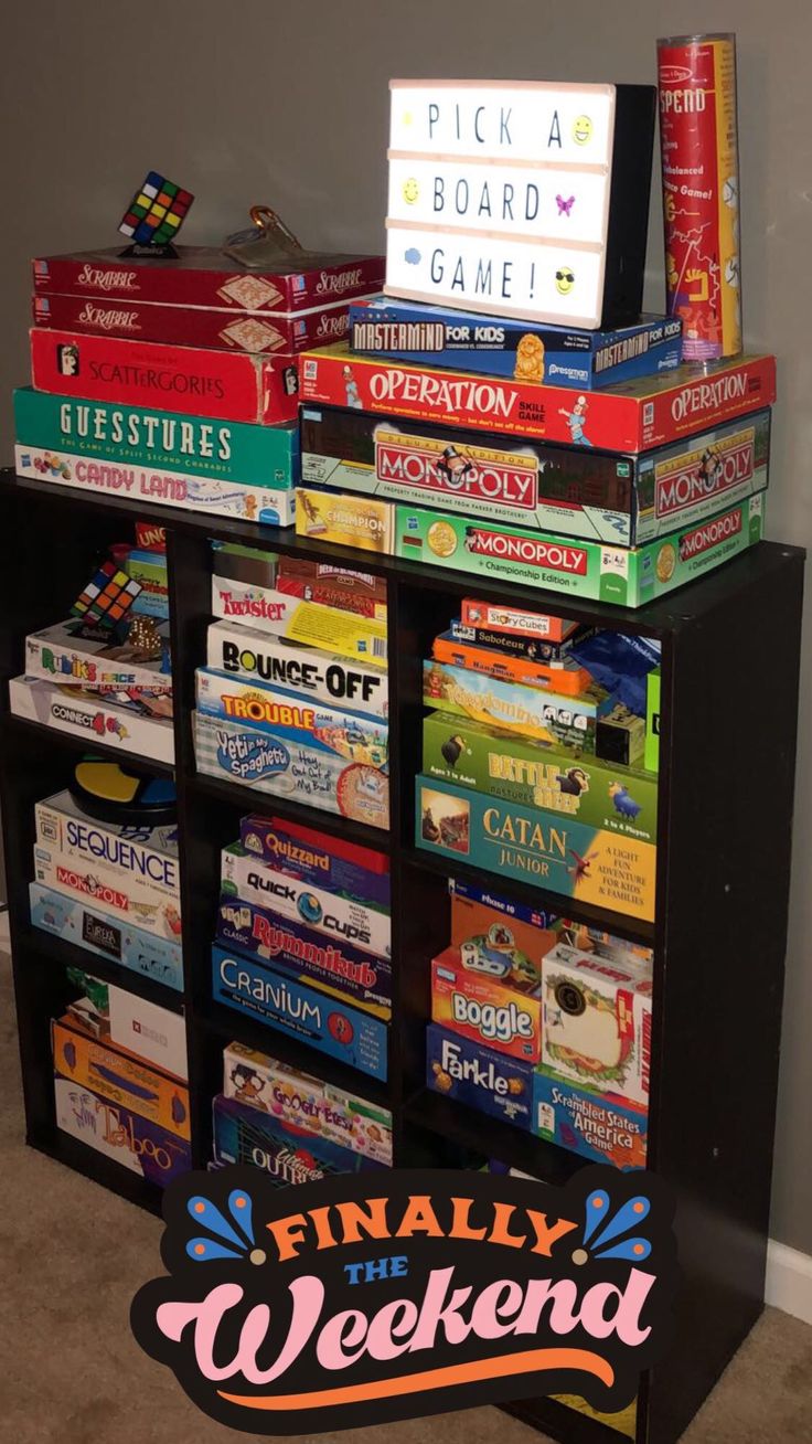 a pile of books sitting on top of a black book shelf next to a wall