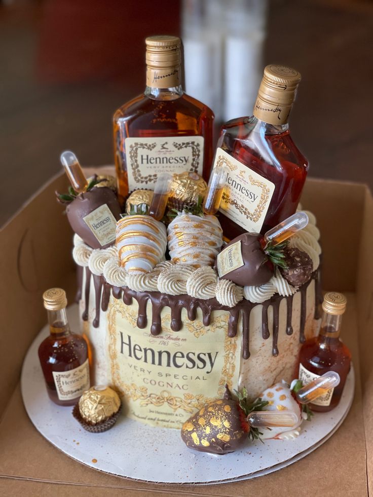 a cake decorated with liquor bottles and candies on top of a cardboard box that says hennessy