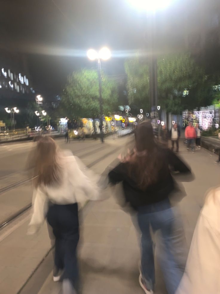 blurry image of two people walking down the street at night with their hands in each other's pockets