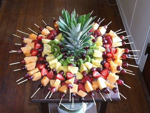 a pineapple surrounded by fruits and skewers