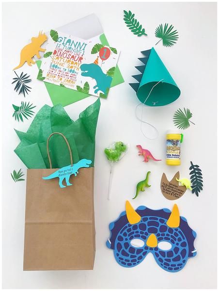 a paper bag with some dinosaur decorations on top of it and other items around it