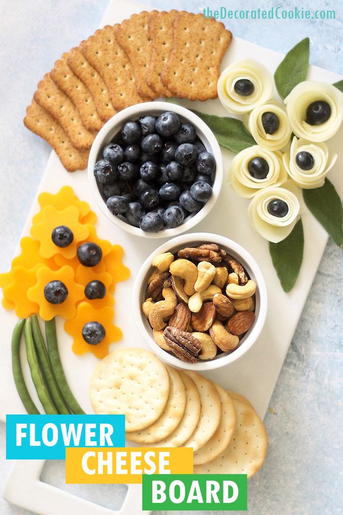 a platter with crackers, grapes, nuts and blueberries