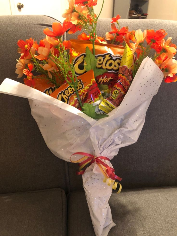 a bouquet of flowers sitting on top of a couch next to some candy and candies