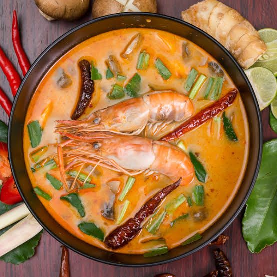 a bowl filled with shrimp and vegetables on top of a wooden table next to other foods