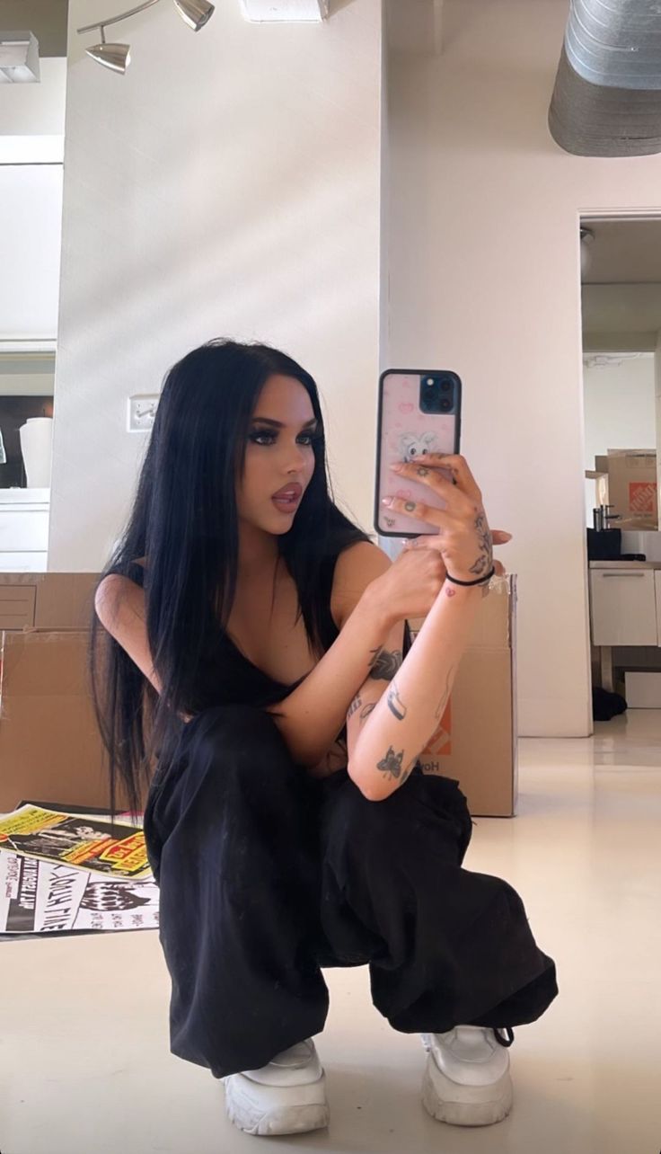 a woman sitting on the floor taking a selfie with her cell phone in hand