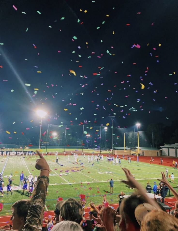 people are throwing confetti in the air on a football field at night time