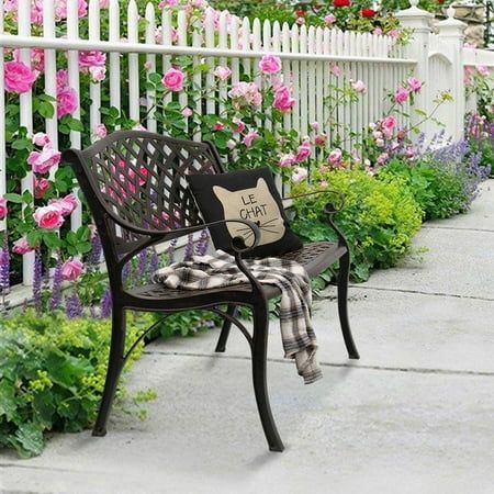 a bench sitting in front of a white picket fence with pink flowers growing on it