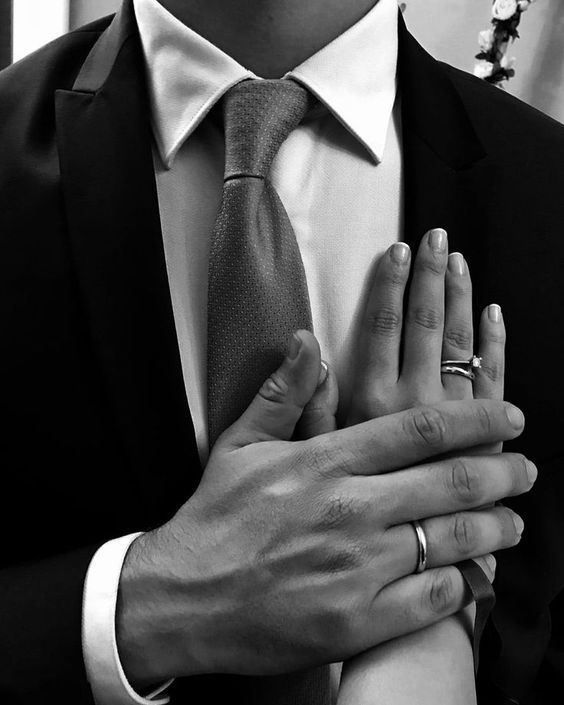 a man in a suit and tie holding his hands together with the other hand on his chest