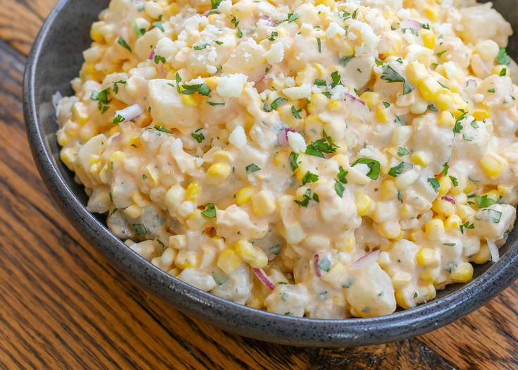 a bowl filled with corn salad on top of a wooden table